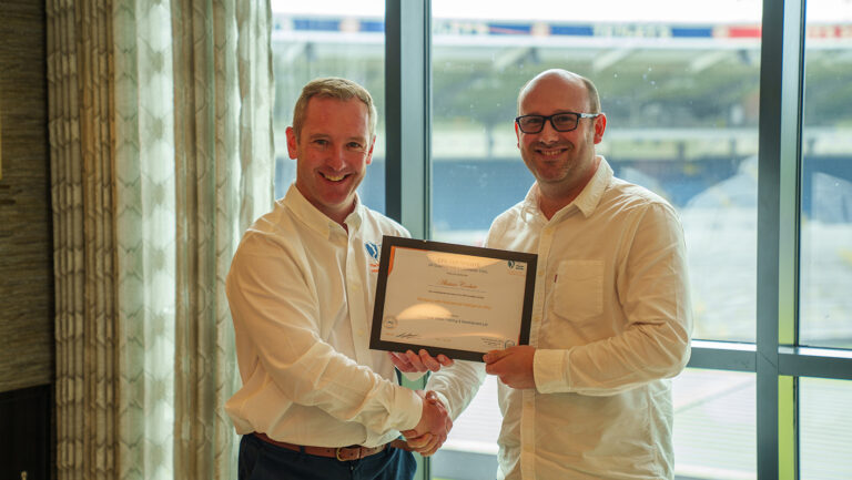 Managing with MQ graduate from Caddick, smiling and holding his certificate next to trainer Alan after completing the programme.