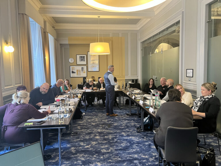 Boardroom group enjoying an interactive coaching session, showing connection and engagement with the content.