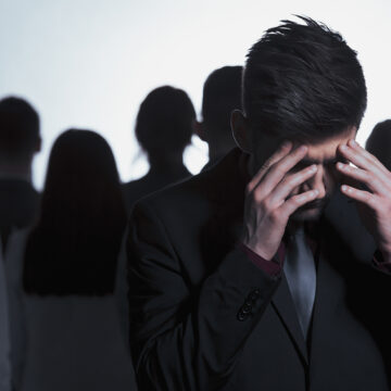 Man sitting with his head in his hand, representing burnout, loneliness, and the emotional challenges faced by male leaders.