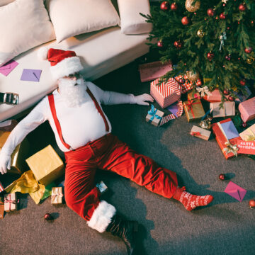 overhead view of tired Santa lying on floor in room with c