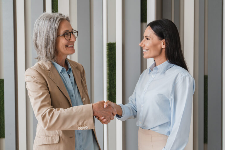 Professional women shaking hands, illustrating collaboration and wellbeing in mental health training.